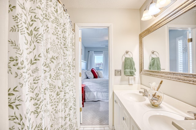 full bath with double vanity, a textured ceiling, ensuite bath, and a sink