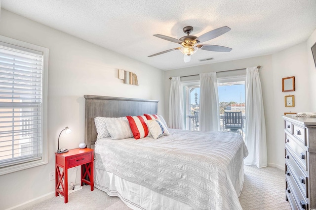 bedroom with visible vents, multiple windows, light carpet, and access to exterior