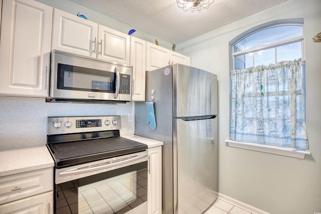 kitchen with baseboards, stainless steel appliances, a textured ceiling, white cabinetry, and backsplash