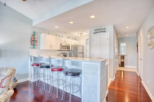 kitchen with dark wood-style floors, appliances with stainless steel finishes, light countertops, and a peninsula