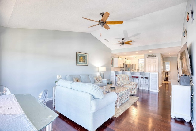 living area with visible vents, dark wood-type flooring, baseboards, lofted ceiling, and ceiling fan