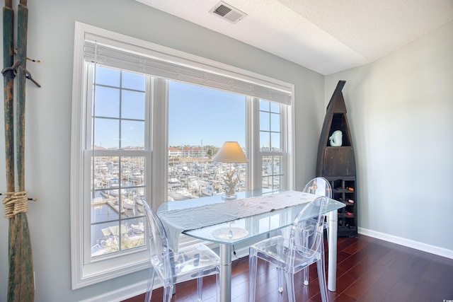 dining area featuring visible vents, a textured ceiling, baseboards, and dark wood-style flooring