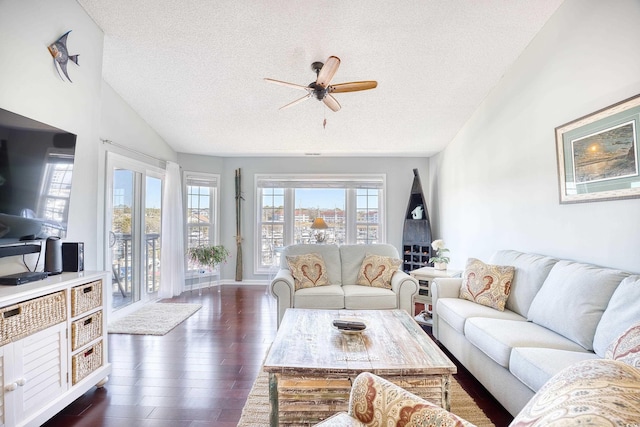 living room with lofted ceiling, dark wood-type flooring, a ceiling fan, and a textured ceiling