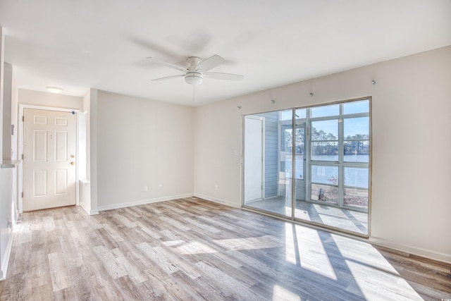 unfurnished room featuring a water view, ceiling fan, and light wood-type flooring