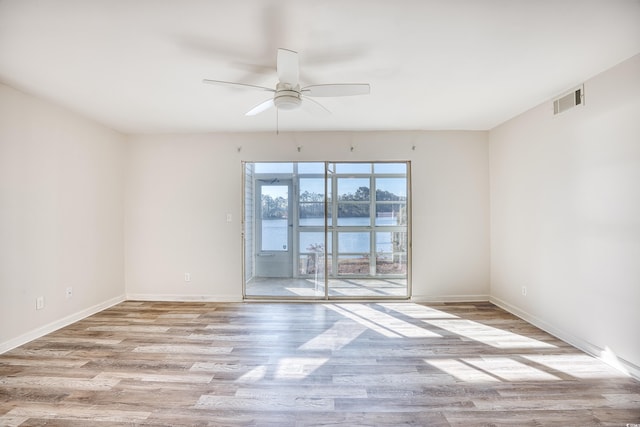 spare room with light hardwood / wood-style flooring, ceiling fan, and a water view