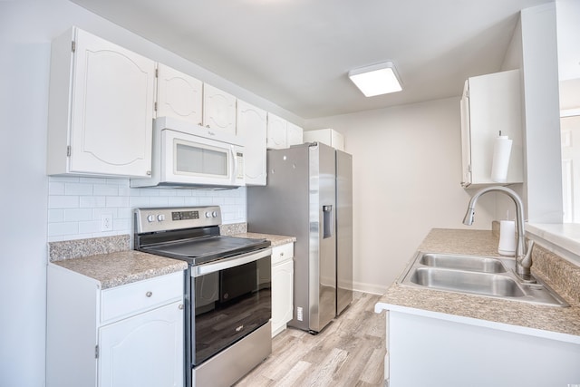 kitchen with sink, light wood-type flooring, stainless steel appliances, decorative backsplash, and white cabinets