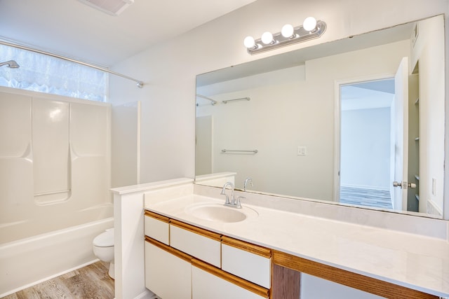 full bathroom with hardwood / wood-style flooring, shower / washtub combination, vanity, and toilet