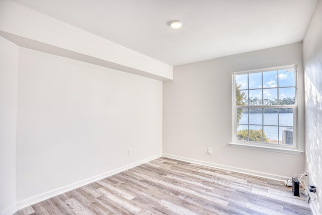 empty room with light hardwood / wood-style flooring and a water view