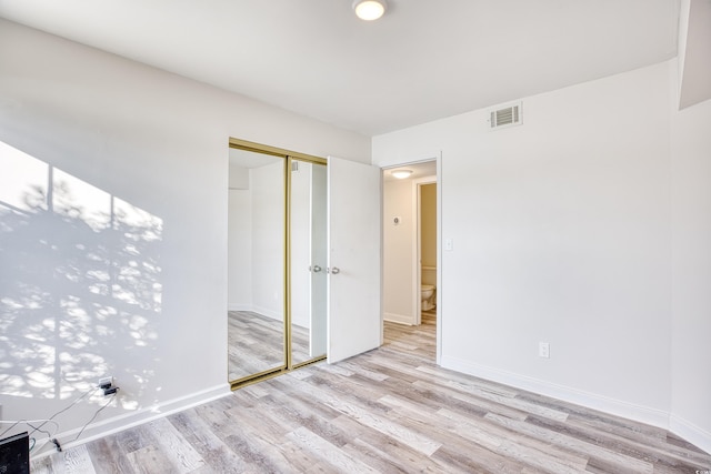 unfurnished bedroom with light hardwood / wood-style floors and a closet