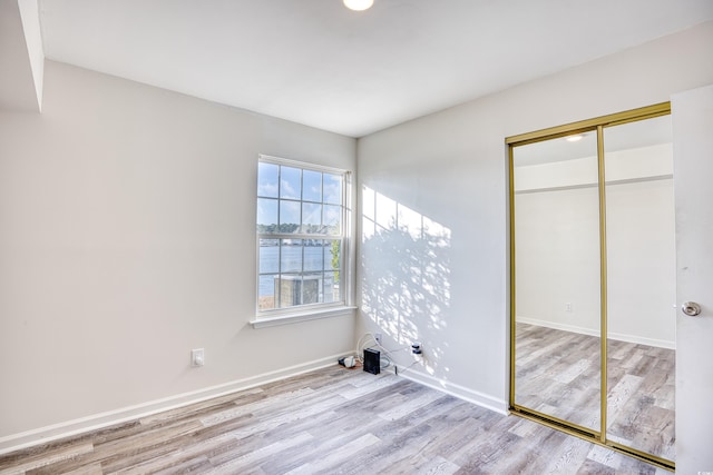 unfurnished bedroom featuring light hardwood / wood-style flooring and a closet