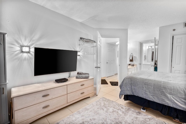 bedroom with connected bathroom, light tile patterned floors, and a textured ceiling