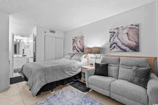 tiled bedroom featuring a closet, a textured ceiling, and ensuite bathroom