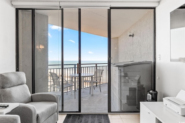 interior space featuring expansive windows, a water view, light tile patterned floors, and a beach view