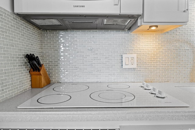 kitchen with tasteful backsplash, white cabinetry, exhaust hood, and white electric stovetop