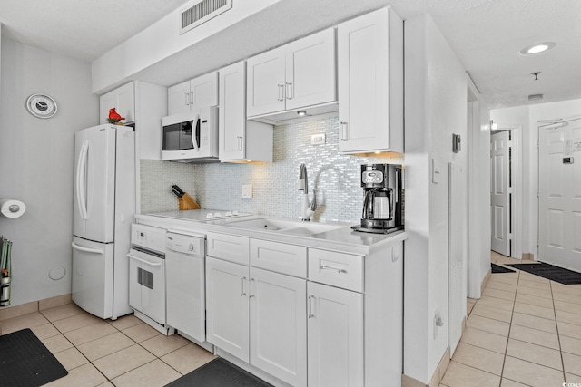 kitchen featuring white cabinetry, sink, white appliances, and light tile patterned floors