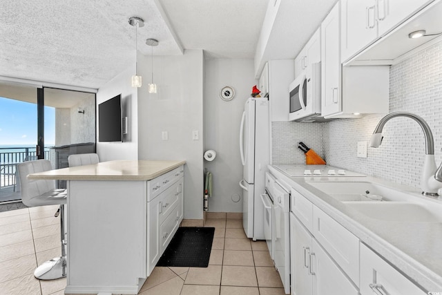 kitchen featuring sink, white cabinets, pendant lighting, white appliances, and backsplash