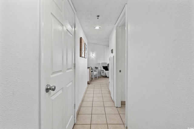 hallway featuring light tile patterned flooring and a textured ceiling