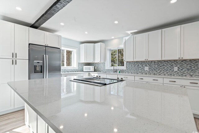 3545 Marion Ln, Murrells Inlet, SC 29576 - kitchen with stainless steel refrigerator with ice dispenser, a spacious island, black electric stovetop, white microwave, and backsplash