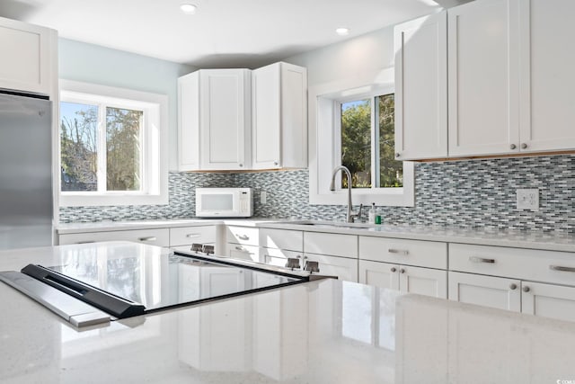 3545 Marion Ln, Murrells Inlet, SC 29576 - kitchen with white microwave, tasteful backsplash, white cabinets, a sink, and light stone countertops