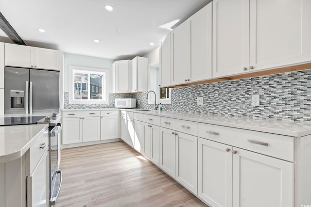 3545 Marion Ln, Murrells Inlet, SC 29576 - kitchen with appliances with stainless steel finishes, decorative backsplash, white cabinets, light wood-style flooring, and recessed lighting