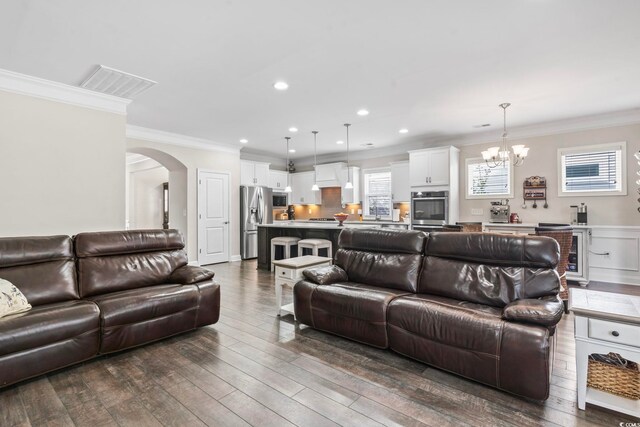 living room with ornamental molding, dark wood-type flooring, and a chandelier