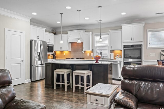 kitchen featuring custom range hood, decorative light fixtures, stainless steel appliances, and a center island