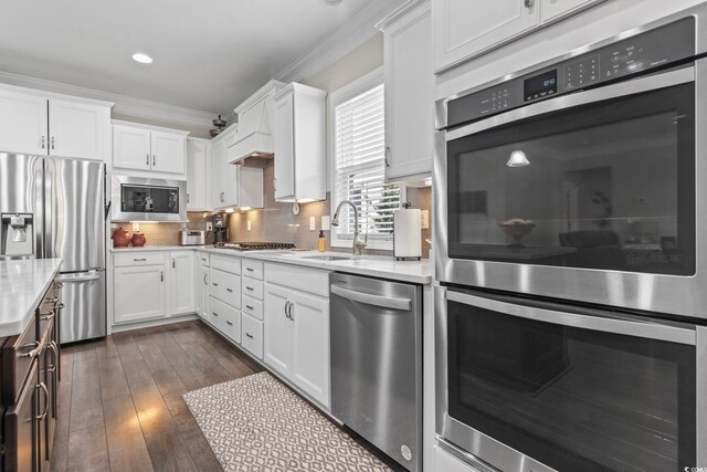 kitchen with white cabinetry, appliances with stainless steel finishes, crown molding, and backsplash