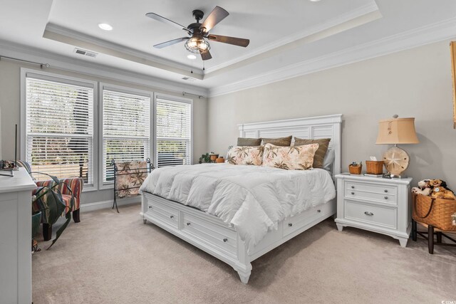 bedroom with crown molding, a tray ceiling, and light carpet