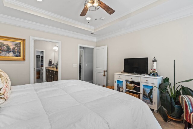 bedroom with a raised ceiling, ornamental molding, connected bathroom, and ceiling fan