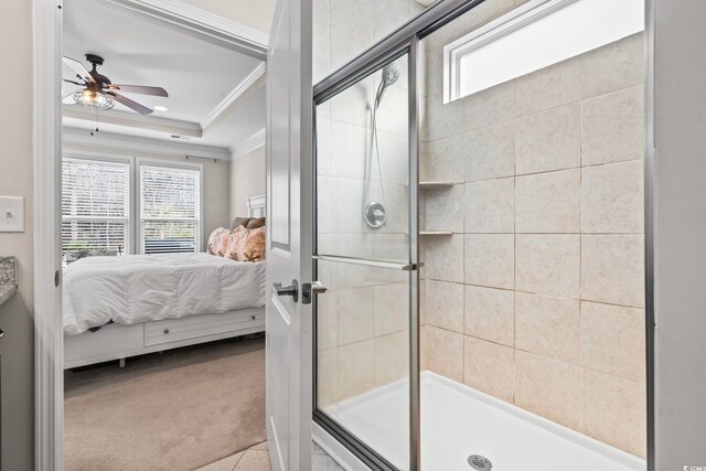 bathroom featuring ceiling fan, ornamental molding, a tray ceiling, and a shower with shower door