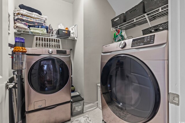 washroom with light tile patterned floors and washing machine and clothes dryer