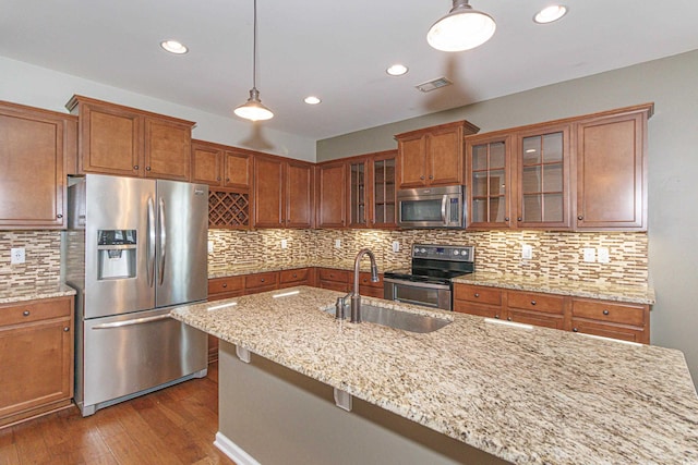 kitchen with stainless steel appliances, light stone countertops, hanging light fixtures, and sink