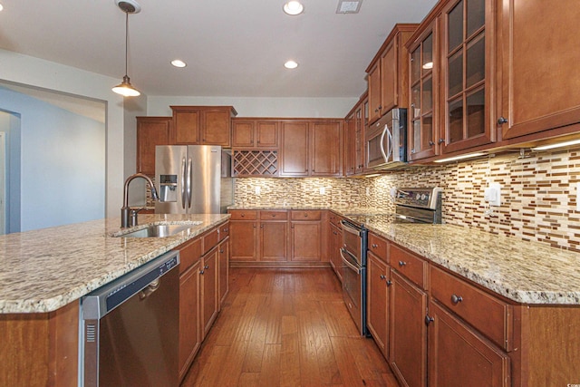 kitchen with sink, backsplash, hanging light fixtures, stainless steel appliances, and dark wood-type flooring