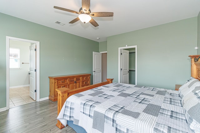 bedroom with ceiling fan, ensuite bathroom, and light wood-type flooring