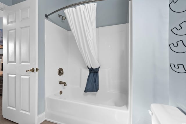 bathroom featuring shower / bathtub combination with curtain and toilet