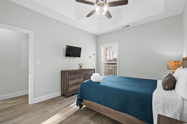 bedroom featuring ceiling fan, a raised ceiling, and light hardwood / wood-style floors