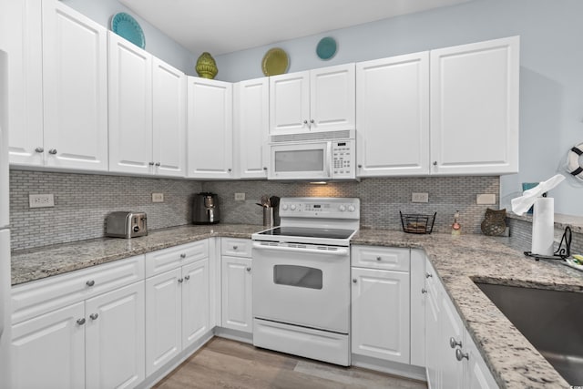 kitchen with tasteful backsplash, white appliances, light hardwood / wood-style flooring, and white cabinets