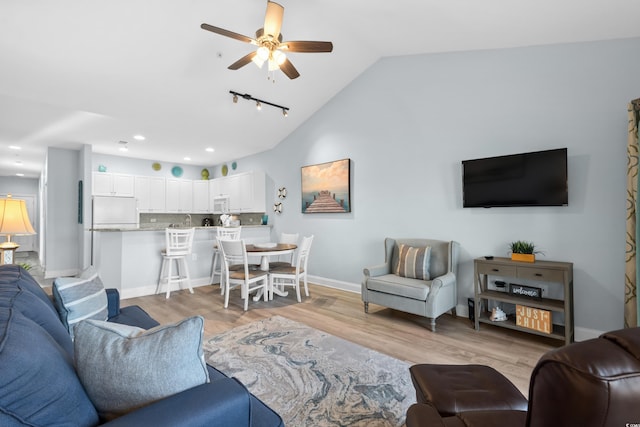 living room with ceiling fan, lofted ceiling, and light hardwood / wood-style floors