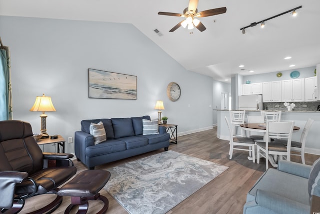 living room featuring hardwood / wood-style flooring, rail lighting, lofted ceiling, and ceiling fan