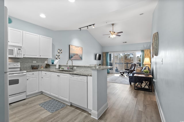 kitchen featuring sink, white cabinets, kitchen peninsula, light stone countertops, and white appliances