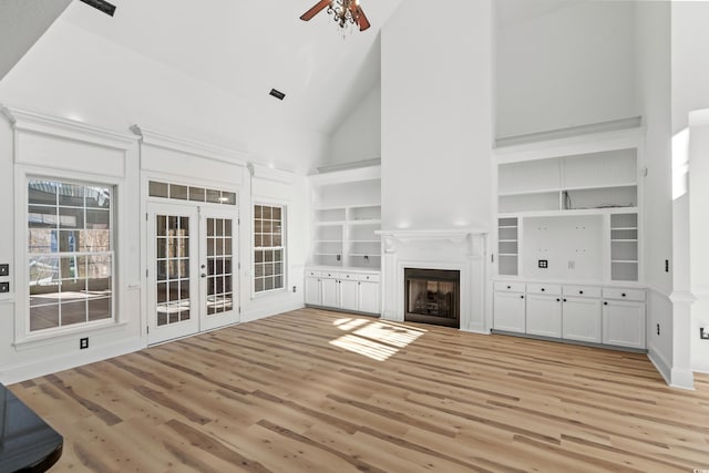 unfurnished living room with french doors, ceiling fan, high vaulted ceiling, and light hardwood / wood-style flooring