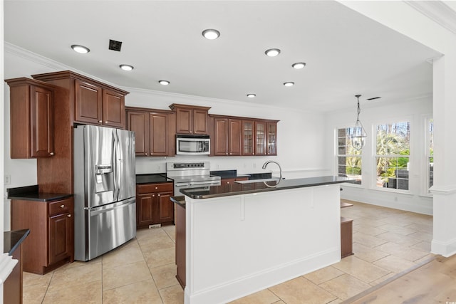 kitchen with light tile patterned flooring, pendant lighting, a kitchen island with sink, stainless steel appliances, and crown molding