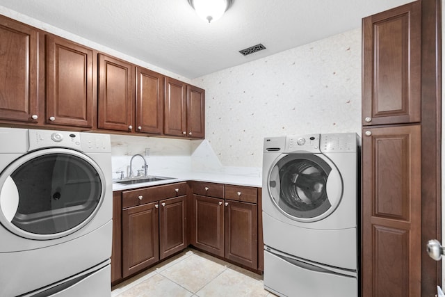 laundry room featuring sink, cabinets, separate washer and dryer, a textured ceiling, and light tile patterned floors