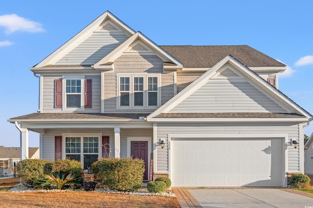 view of front of house featuring an attached garage, covered porch, a shingled roof, and concrete driveway