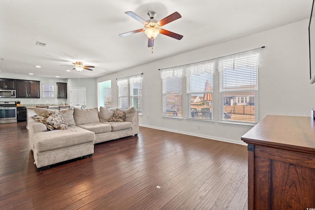 living room featuring baseboards, ceiling fan, dark wood finished floors, and a healthy amount of sunlight