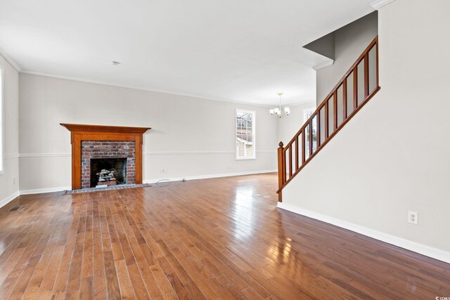 112 Staton Ln, Longs, SC 29568 - unfurnished living room featuring stairs, a chandelier, wood finished floors, a brick fireplace, and ornamental molding