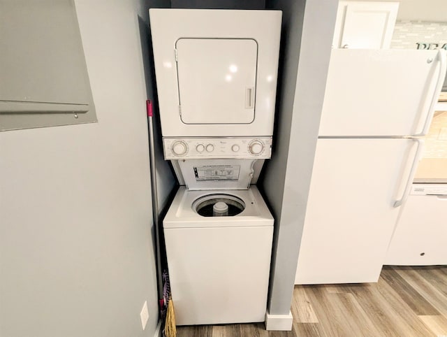 washroom featuring stacked washing maching and dryer and light hardwood / wood-style flooring