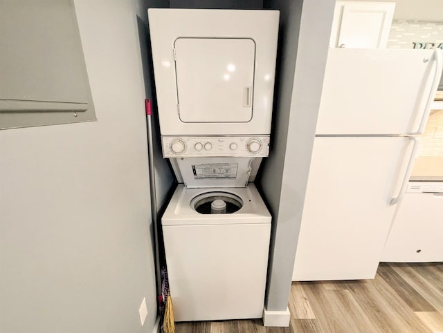 laundry area featuring light wood-type flooring, stacked washer / dryer, and laundry area