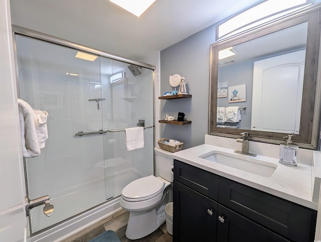 bathroom with toilet, a stall shower, wood finished floors, and vanity