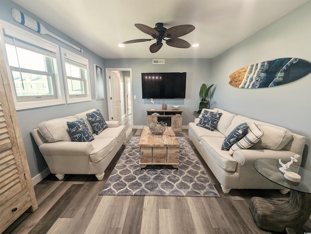 living room featuring baseboards, visible vents, wood finished floors, and a ceiling fan